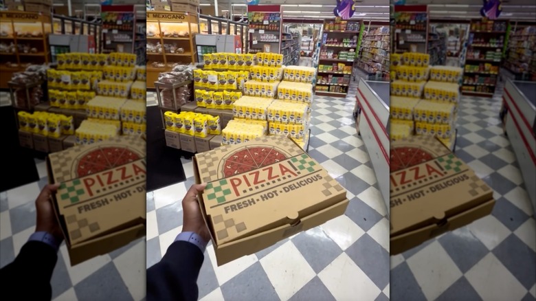 Person holding a pizza box inside Pizza by Yandy's