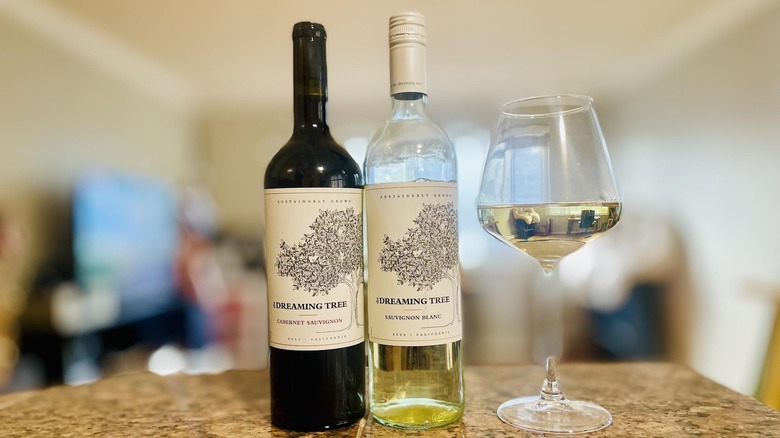 Bottles of Dreaming Tree Cabernet and Sauvignon Blancs with a glass of white wine
