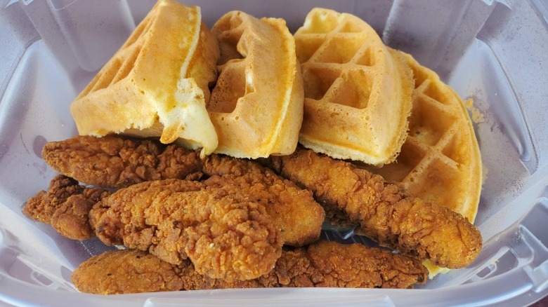 Belgian waffle quarters with chicken strips from IHOP in a clear takeout container.