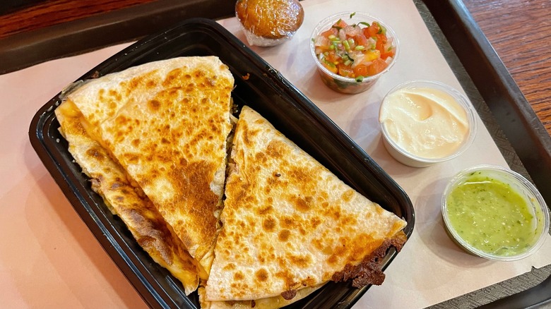 A beautifully crispy quesadilla with sides of sour cream, salsa verde, and pico de gallo