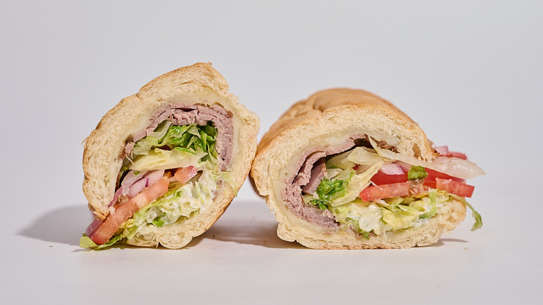 A Subway roast beef sandwich sliced in half on a table