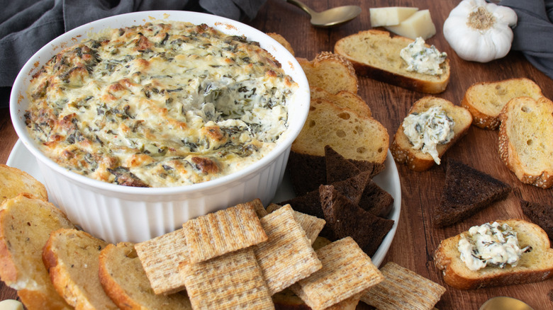 bowl of cheese dip with sliced breads and crackers