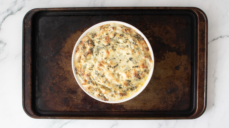 baked cheese dip in a round white pan on top of a baking sheet