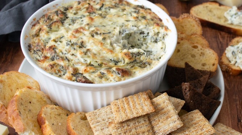 hand using a spoon to scoop up cheese dip