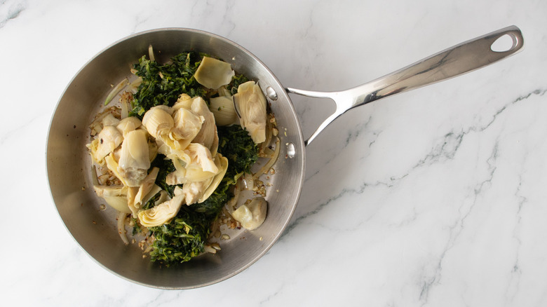 spinach and artichoke hearts in a frying pan