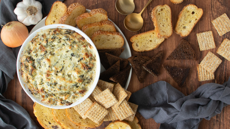 bowl of cheese dip with sliced breads and crackers