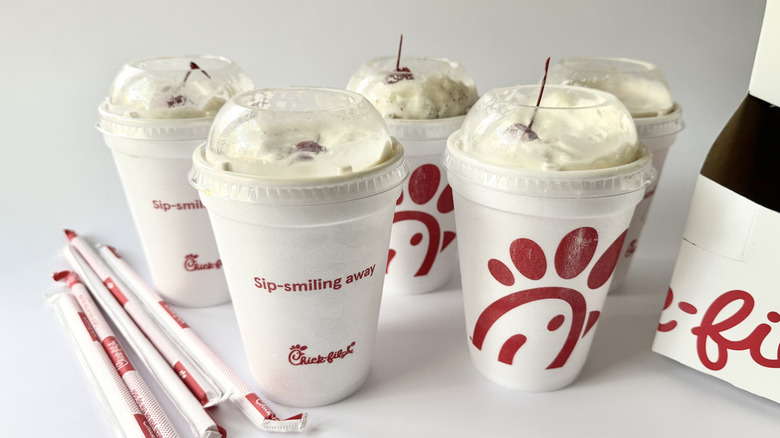Two rows of milkshakes from Chick-fil-A next to the to-go box and straws