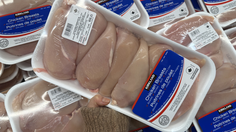 Hand holding a package of Kirkland Signature Fresh Boneless Skinless Chicken Breasts