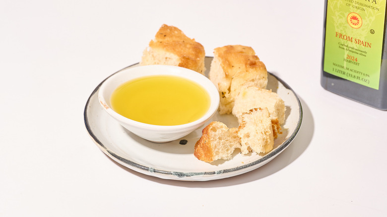 bowl of olive oil on a plate surrounded by bread