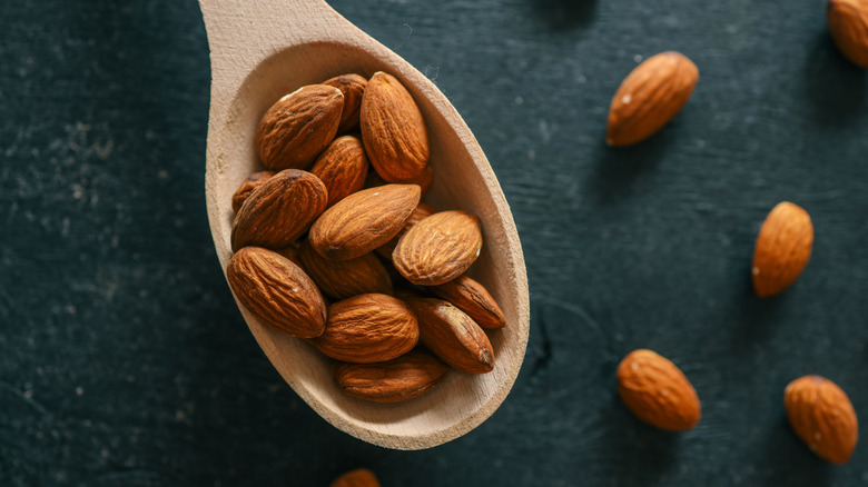 A wooden spoon full of almonds