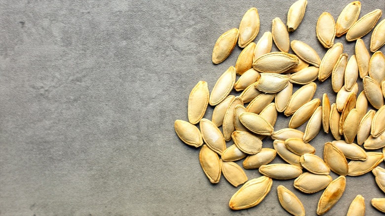 Loose pile of roasted pumpkin seeds on a gray surface