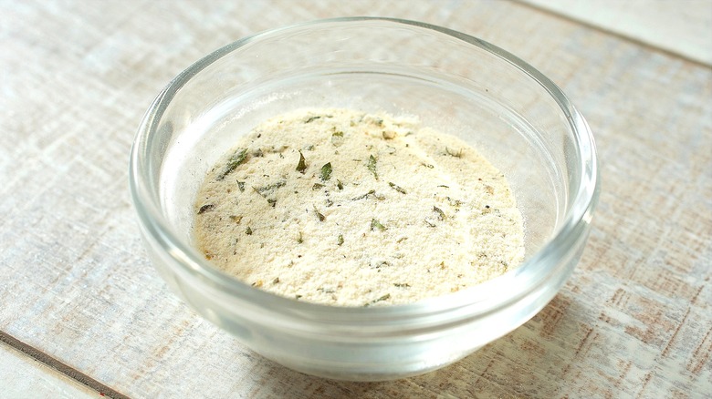 Powdered ranch seasoning in a small clear bowl on a white-washed wooden table