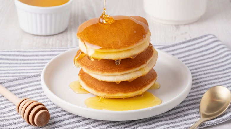 Honey being poured on a stack of pancakes