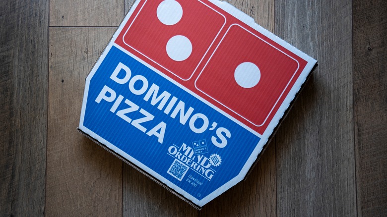 A Domino's pizza box on a wood floor