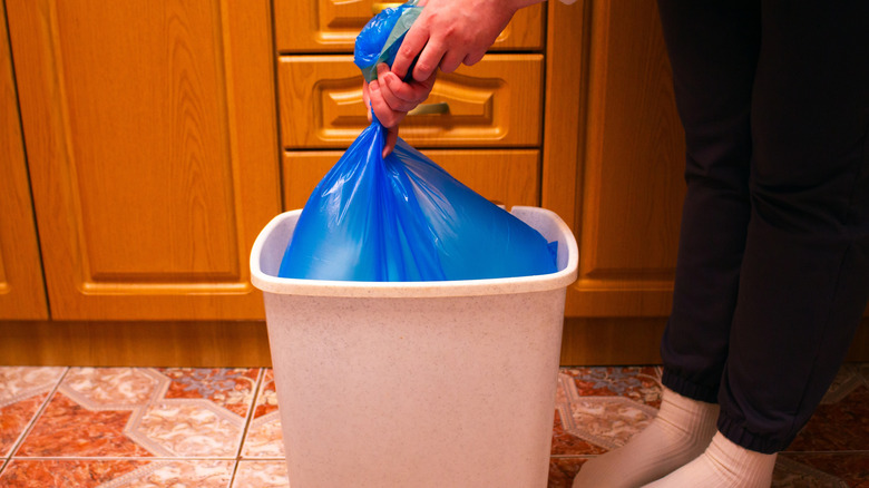 Person taking trash bag out of a trash can