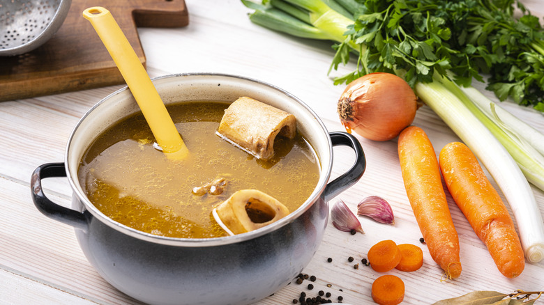 Heaping of bone broth next to fresh vegetables