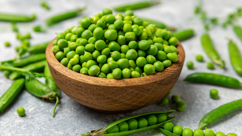 Fresh green pea pods with peas in a bowl