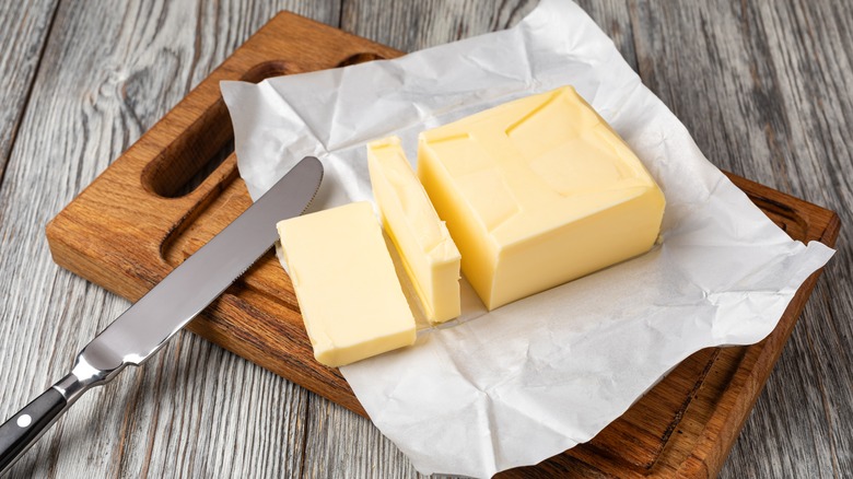 An open pack of butter on a cutting board with a knife