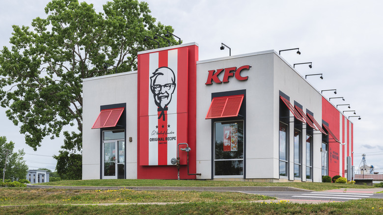 A KFC restaurant in a grassy area next to a tree