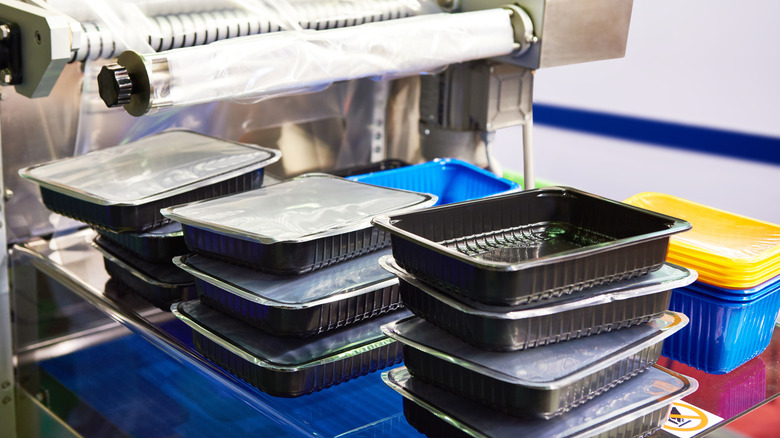Multiple black food tray containers at food packing facility.