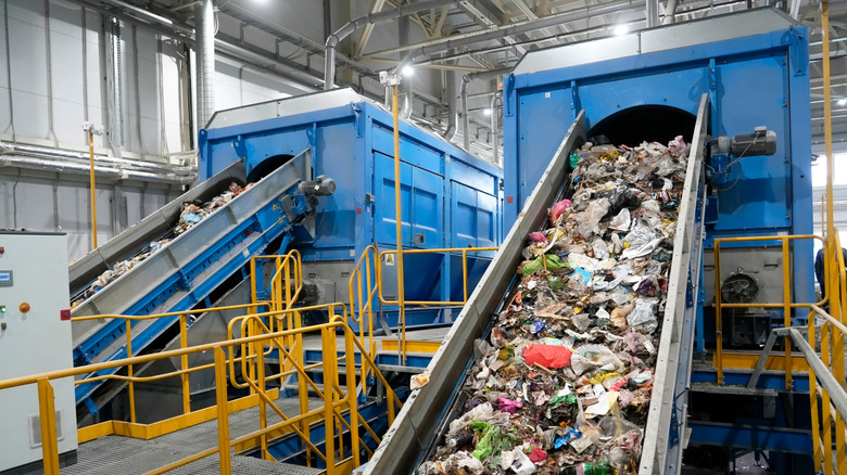 Inside of a recycling facility with recycling materials being moved into sorting containers.