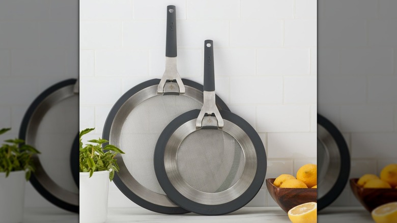 Miu-2-piece-silicone-splatter-guards against white tile next to a plant and a bowl of lemons