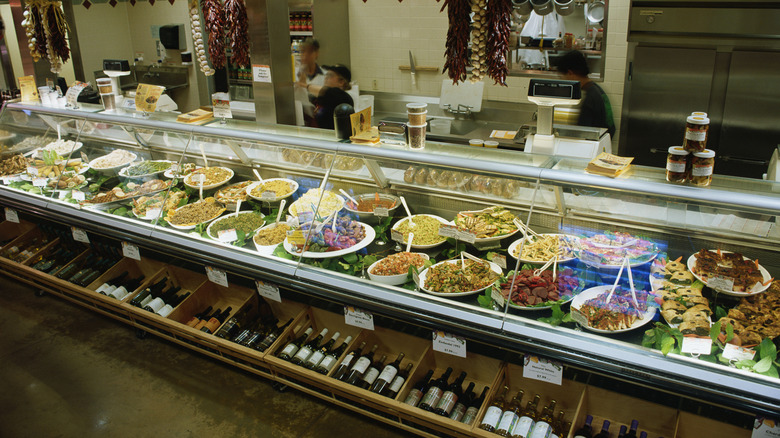 Many prepared foods behind glass at a deli counter.
