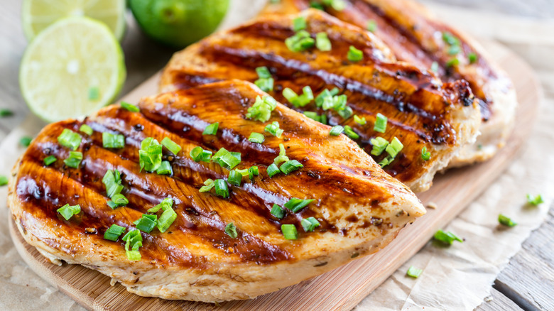 Lime-grilled chicken resting on a wooden cutting board