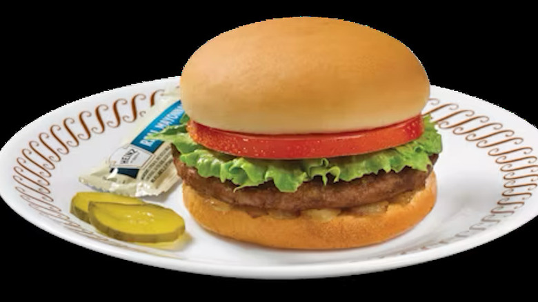 a cheeseburger on a plate with pickles