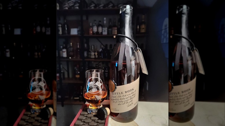 Bottle of Little Book Bourbon with glass on counter.