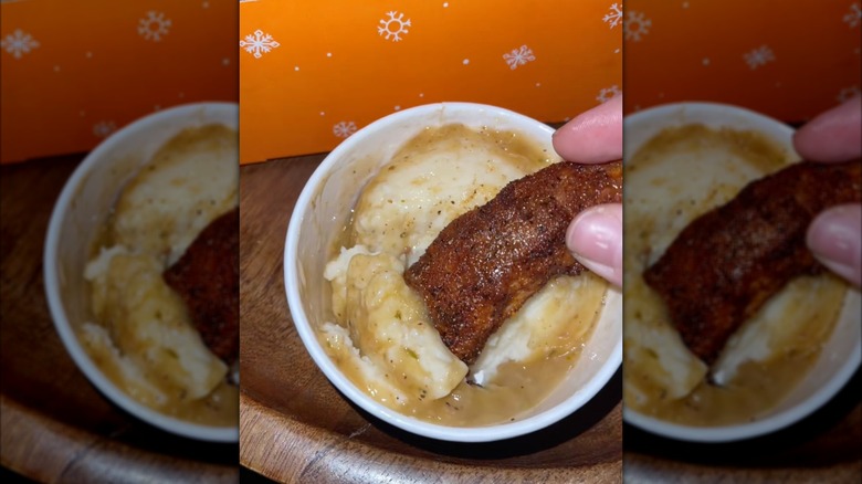 Popeyes tender being dunked in mashed potatoes