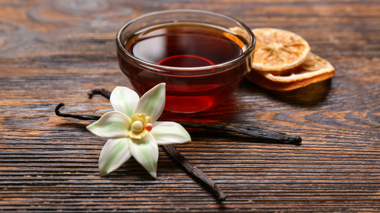 vanilla bean and bowl of extract on wooden table
