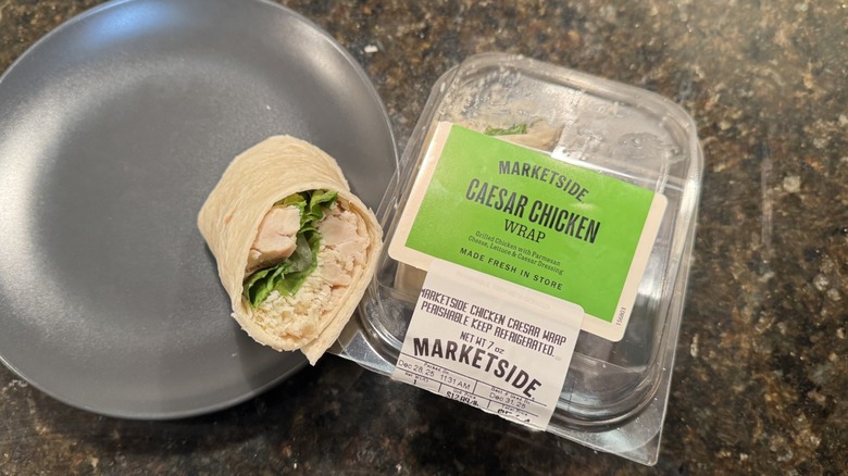 Caesar chicken wrap on gray plate beside packaging