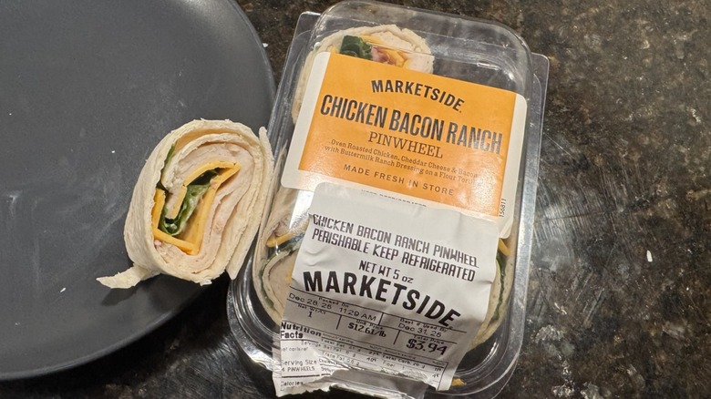 Chicken bacon ranch pinwheel on gray plate beside packaging