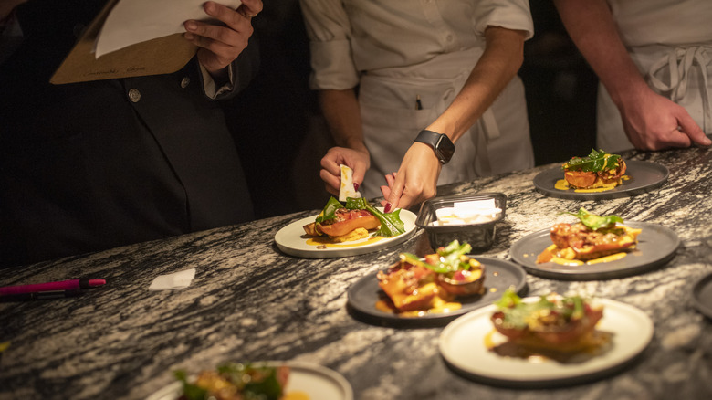 A chef's hands are seen plating food at Crown Shy restaurant.