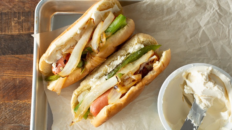 2 Seattle hot dogs on a tray next to a container of cream cheese