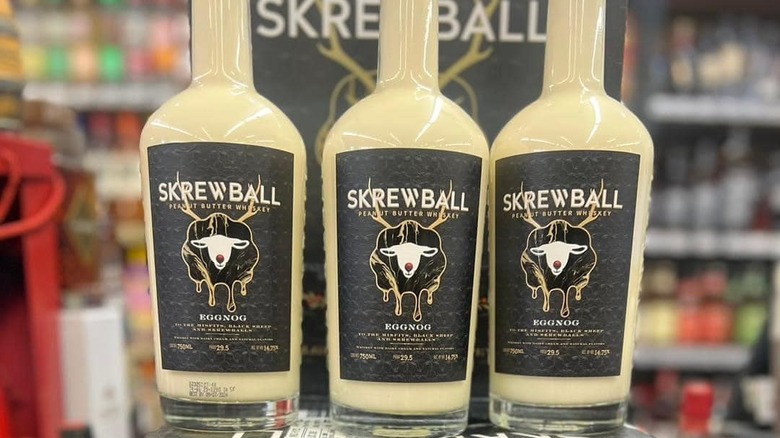 Three bottles of Skrewball Peanut Butter Whiskey Eggnog in a store display