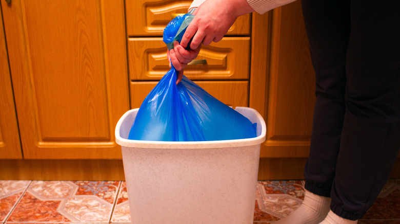Woman taking a trash bag out of a trash can