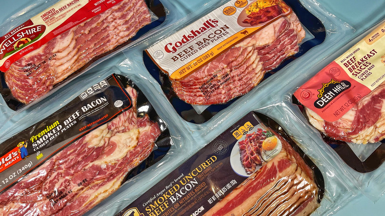 Several packages of raw beef bacon arranged on a light blue background