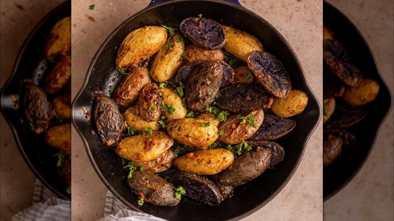 Cast iron pan with roasted fingerling potatoes topped with fresh herbs.
