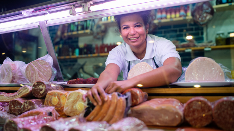 A female butcher working in a display case of fresh meats