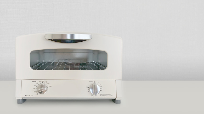 A white toaster oven sits on a white counter against a white background