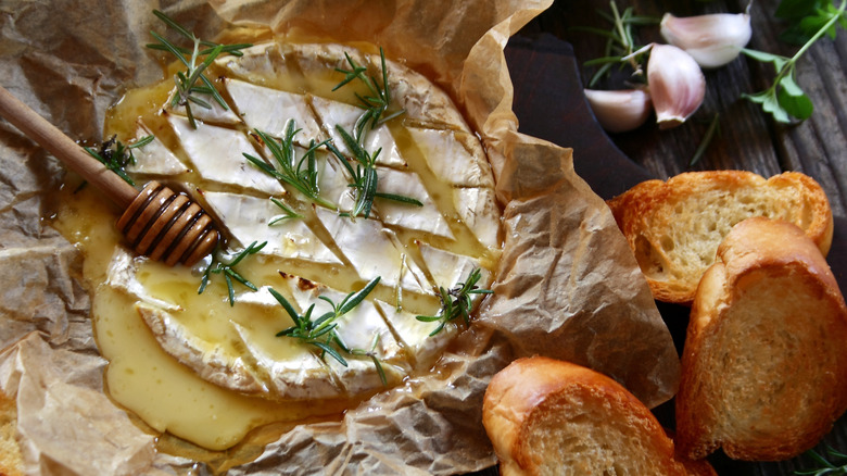 A lovely baked brie is covered with honey and served with toasted baguette slices.