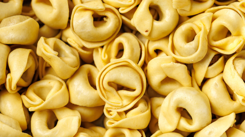A pile of freshly made Tortellini pasta pieces stacked on top of each other.
