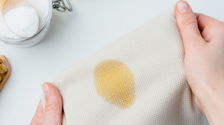 A person holding a fabric with an oil stain.
