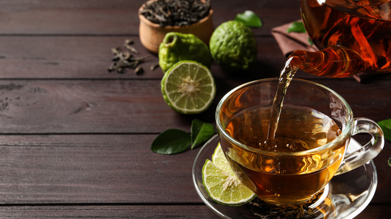 Earl Grey being poured into a clear glass, with fresh ingredients in the background highlighting its flavor notes.