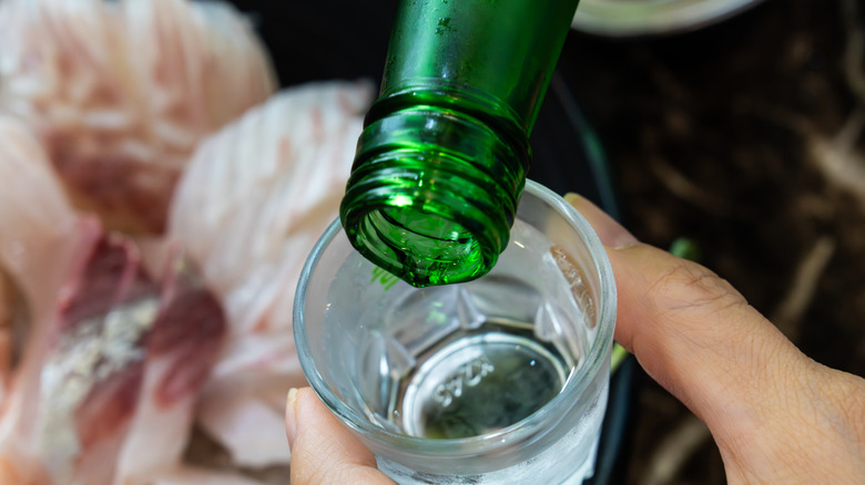 Soju being poured into a shot glass.