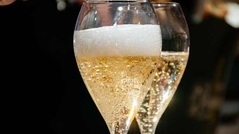 Two flute glasses of fizzy Prosecco, one placed slightly behind the other.