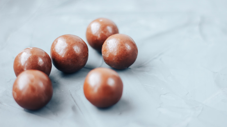 A close up of six milk chocolate balls on a tabletop