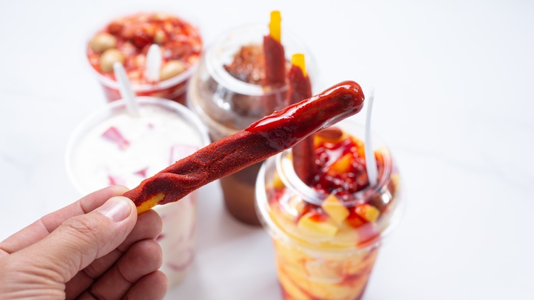 Person holding a tamarind straw candy over drink glasses